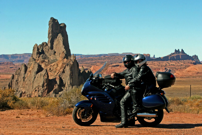 Couple on the motorbike agains the desert landscape background